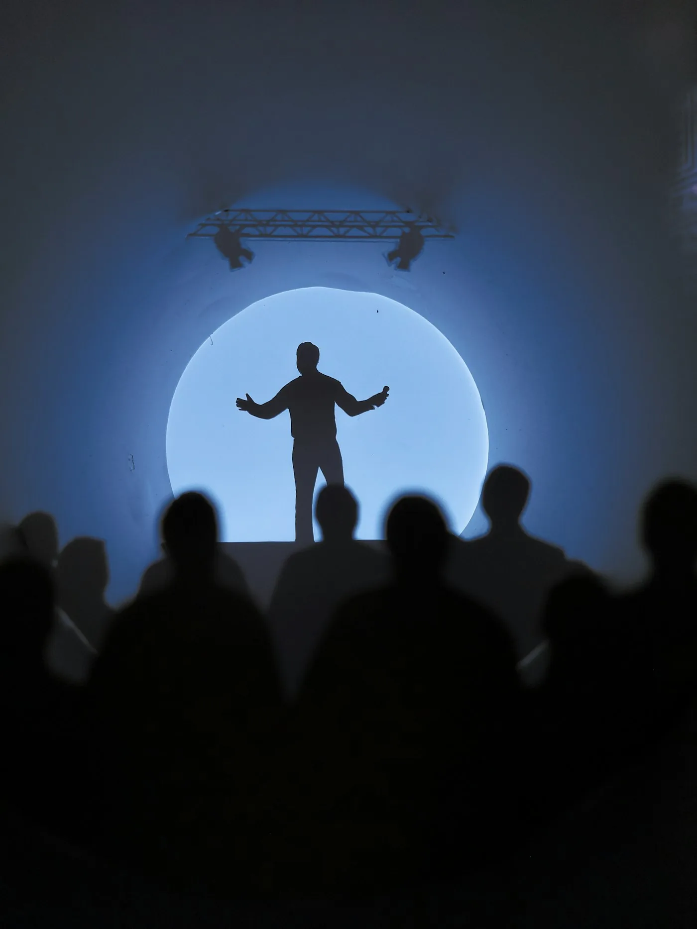 Singer silhouetted before a crowd at dusk