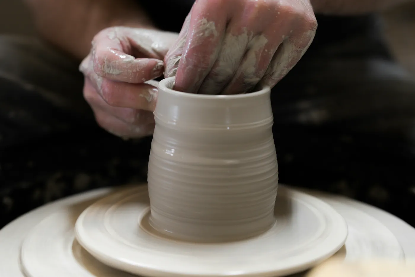 Potter's hands shaping clay on the wheel